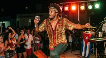 Cuban funk musician performing energetically with colorful stage lights