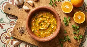 Mojo criollo cubano en pilón de barro con ajo, naranja agria y especias