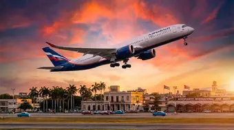 Russian aircraft departing from a Cuban airport with palm trees in the background at sunset