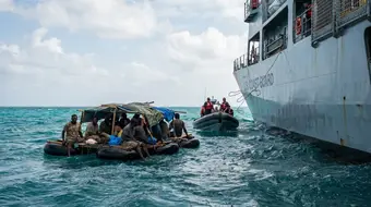 Cuban rafters being rescued at sea in the Caribbean by a larger vessel