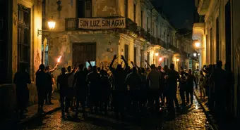 Frustrated crowd in a dark Cuban street at night under emergency lights