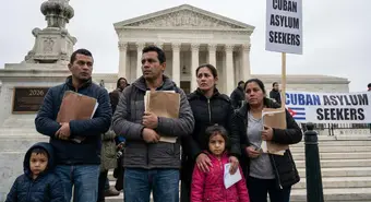 Worried Cuban migrants outside the Supreme Court building holding legal documents