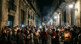 People in a dark Cuban street at night, only lit by candles during a massive blackout
