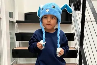 Liam Conejo Ramos wearing a blue bunny hat near his Minneapolis home with federal agents in the background