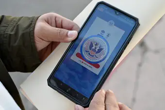 Asylum seeker reviewing CBP One app at the El Chaparral border crossing in Tijuana, Mexico