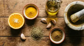 Essential Cuban condiments on a wooden table: sour orange, bijol, garlic, and spices