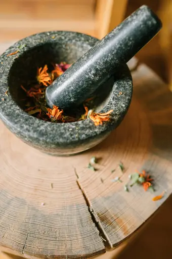 Fresh medicinal herbs in a granite mortar on a wooden board. Photo: Pexels