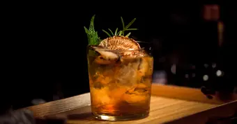 Glass of aged Cuban rum with ice on a wooden bar