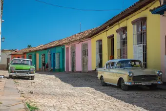 Calle colonial de Trinidad, Cuba, con autos clásicos y edificios coloridos. Foto: Pexels
