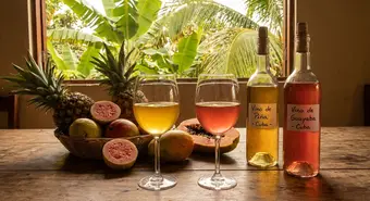 Glasses of Cuban tropical fruit wine beside fresh fruits on a rustic wooden table